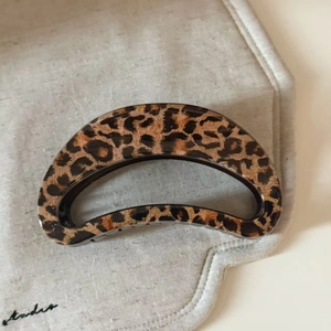 Close-up of a leopard print hair claw clip on a textured beige linen background