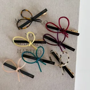 Vue à plat de pinces à cheveux à nœuds en acétate coloré avec attaches en métal doré