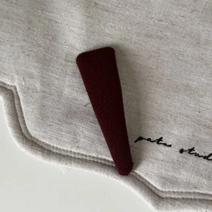 Macro shot of vintage wine red knitted fabric triangular hair clip with ribbed texture