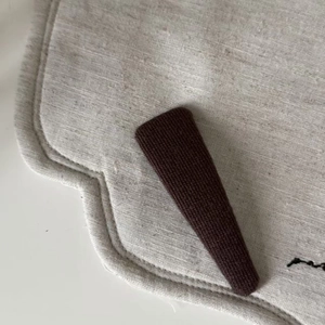 Close-up of vintage reddish-brown knitted fabric hair clip with detailed woven texture