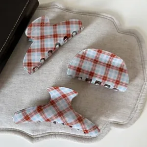 Three-piece set of vintage red and blue plaid acetate claw clips on a linen mat