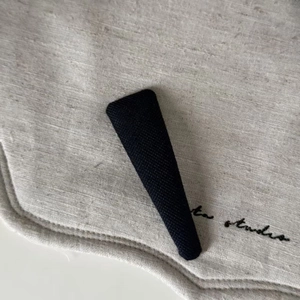 Detailed macro shot of vintage black knit fabric covered BB hair clip on linen background