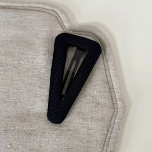 Close-up of minimalist black triangular fabric hair clip with a clean metal spring structure