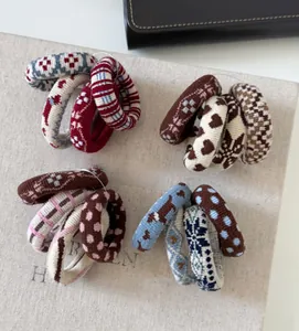 Detail of four knitted elastic hair ties with festive patterns in red, blue, and beige colors