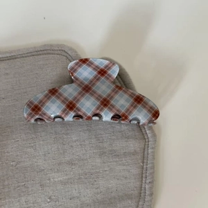 Detail view of vintage brown and blue plaid acetate hair claw clip on linen background