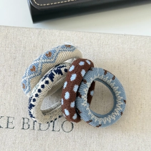 Close-up of four knitted elastic scrunchies with heart patterns and textured woven fabric