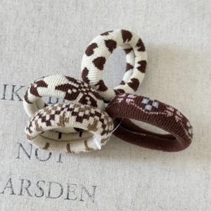 Detailed macro view of four elastic knit hair ties in brown and beige earth tones