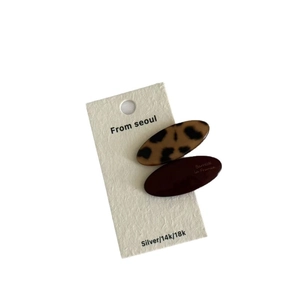 Set of two leopard print and solid brown acetate hair clips on a white display card