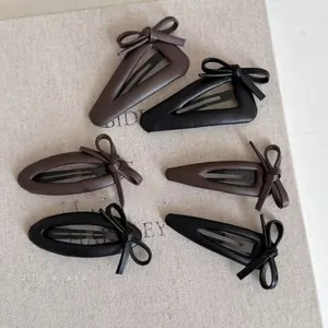 Close-up of brown and black leather bow hair clips in various shapes on a vintage fabric
