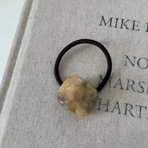 Close-up of geometric acetate cube hair tie with brown marble texture on elastic band