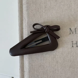 Close-up of a vintage dark brown bow hair clip with leather texture and triangle base