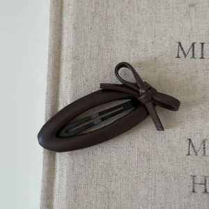 Detail shot of the dark brown leather bow hair clip with a classic metal BB clip base