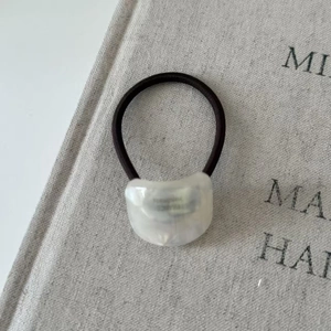 Close-up of geometric acetate hair tie with a minimalist white resin bead on a book