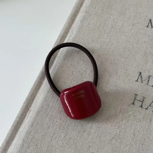 Close-up of handmade burgundy geometric resin block on black elastic hair tie