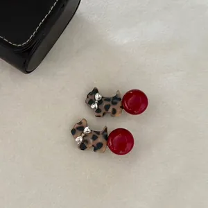 Fashionable leopard print dog hair clip with red bead accent on plush background
