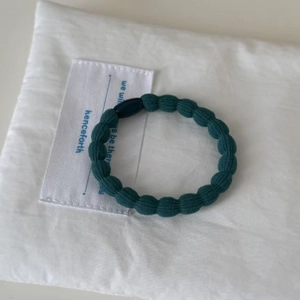 Durable dark green elastic hair tie with ribbed texture and minimalist bead clasp