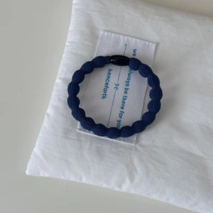 Deep blue ribbed hair scrunchie with black resin bead on a minimalist white backdrop