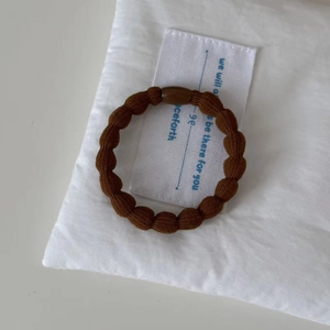 Detail of durable dark brown elastic hair tie with glossy resin buckle and textured weave