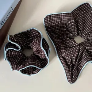 Brown and white checkered scrunchies with light blue edge piping set on minimalist book
