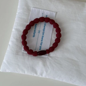 Close-up of wine red braided elastic hair tie with a decorative polished resin bead detail