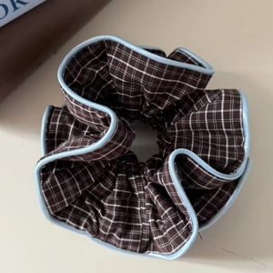 Detail of blue and brown checkered scrunchie with contrast piping on soft fabric
