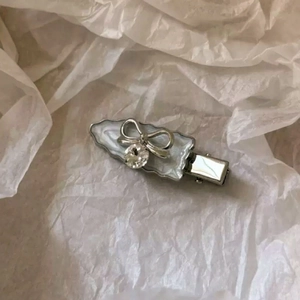 Elegant bow hair clip with silver alloy, white enamel, and a sparkling crystal center