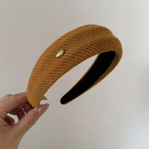 Detail of knitted mustard yellow headband with golden 'love' metal buckle accent