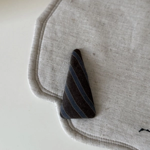 Macro shot of vintage striped triangular hair clip on natural beige linen background