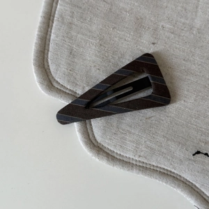 Detail of retro striped triangular hair clip in brown and grey on linen background