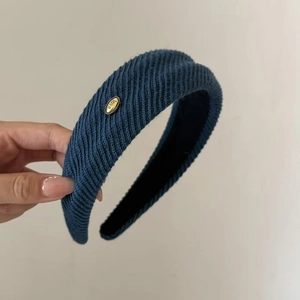 Detail of grey-blue ribbed knit headband with gold oval buckle featuring love engraving