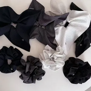 Detail view of navy blue striped hair scrunchies and bow headband with handmade labels