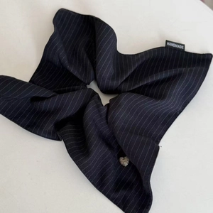 Detailed shot of navy heart striped scrunchie with handmade tag and silver heart charm