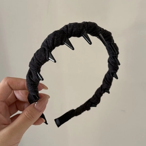 Close-up of black denim headband with metallic conical spikes for a punk aesthetic