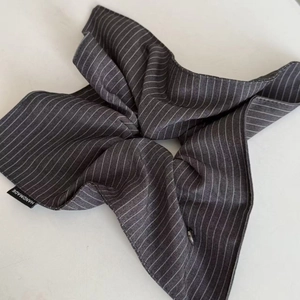 Detail view of navy blue striped scrunchie fabric with a handmade black woven label