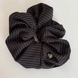 Macro shot of navy blue striped scrunchie with a silver sparkling heart-shaped charm detail