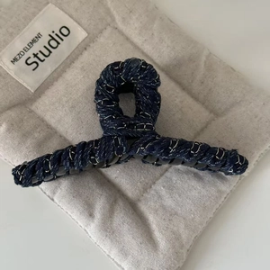 Denim bow hair claw clip with silver chain wrap for thick hair shown on a padded background