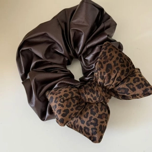 Detail view of the brown PU leather and leopard print fabric textures on the hair scrunchie