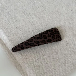 Triangle leopard print hair clip with knit texture on minimalist fabric background