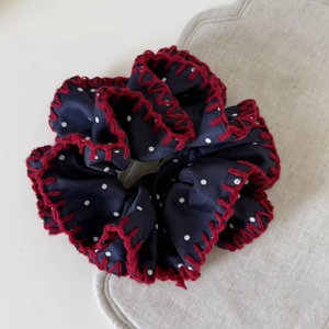 Vue détaillée du chouchou à pois bleus avec bordure au crochet rouge et fini satiné