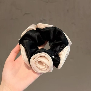 Détail d'un chouchou noir avec des roses en gaze crème et de petites perles blanches
