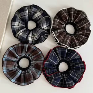 Set of four preppy style plaid scrunchies in black, brown, blue, and navy patterns