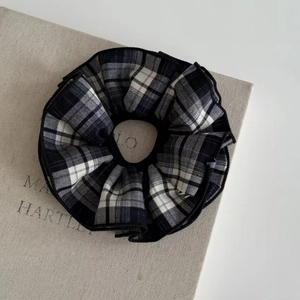 Classic black and white plaid scrunchie hair tie on a minimalist beige background