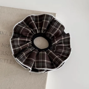 Close-up of brown plaid scrunchie with white scalloped edges and soft fabric texture