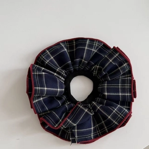 Detail of blue plaid hair scrunchie with red stitching and checkered fabric texture