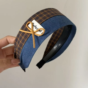 Detail of blue denim and plaid headband featuring a yellow bow and lucky girl tag
