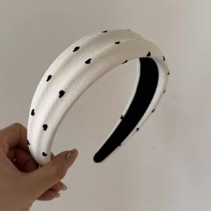Detail of wide cream headband featuring black heart embroidery and non-slip inner lining