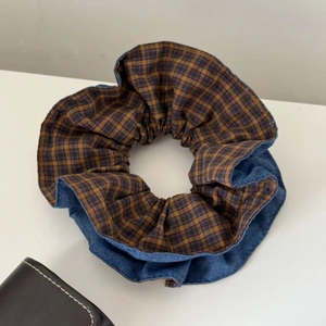 Close-up of denim and plaid patchwork oversized scrunchie hair tie with fabric texture