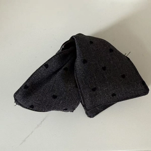 Detailed close-up of a black heart-shaped fabric clip with dotted texture on marble