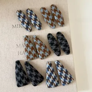 Detail of houndstooth knit hair clips set with oval and triangle shapes for autumn winter
