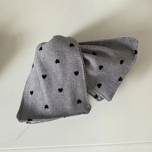 Detail of grey houndstooth fabric headband with black velvet heart patterns texture